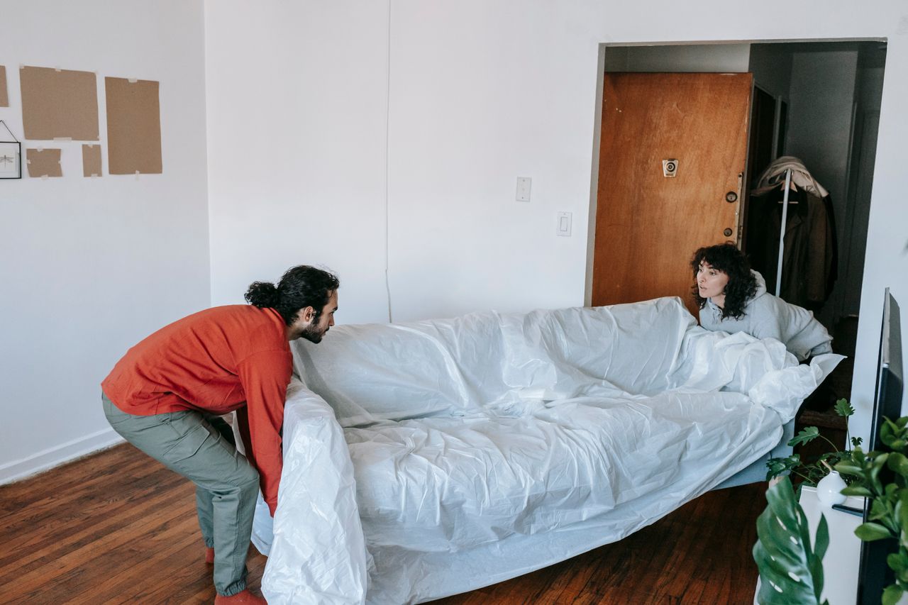 about-02 A couple collaboratively lifting a couch while moving into a new apartment.